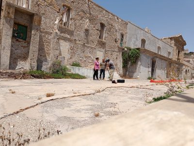 3 students set up a surveying tripod at an ancient site