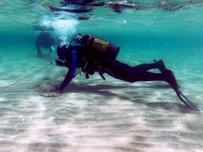2 scuba divers on the lake bed holding a rope