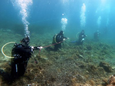 4 scuba divers on the lake bed holding a rope