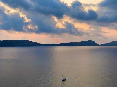 Study Tour of Greece lake and hills with sun setting and a single sailboat