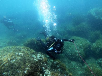 2 scuba divers on the lake bed surveying rock