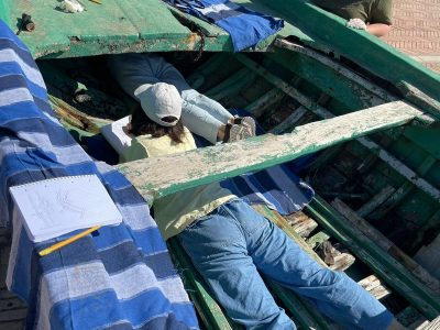 3 archeologist students in an old green wooden boat