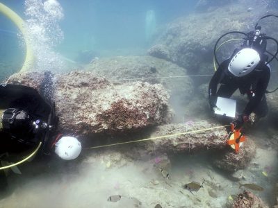 2 scuba divers measuring an underwater stone
