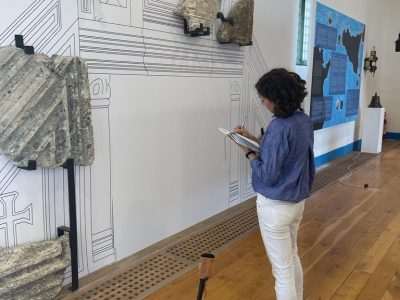 Student documents ancient rocks on a wall that is trying to reconstruct what the positions were