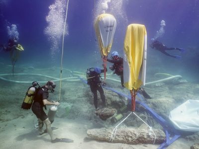 2 scuba divers lifting an artifact underwater balloons
