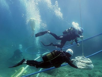 2 scuba divers transporting an artifact underwater