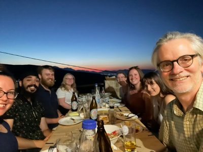 7 students and professor enjoying dinner outside at night in Gournia