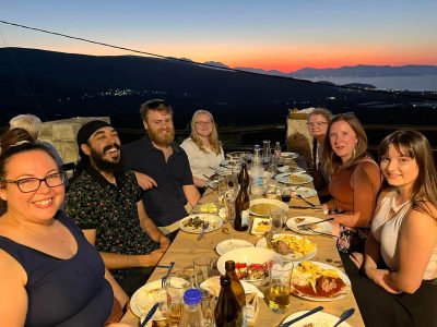 7 students enjoying dinner outside at night in Gournia