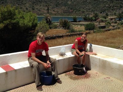 2 students wearing Brock University T-shirts sifting through water in black buckets