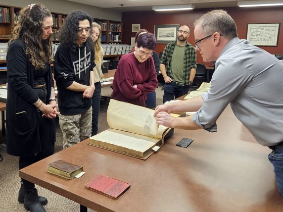 Mensa Latina students look at manuscripts with David Sharron in Special Collections