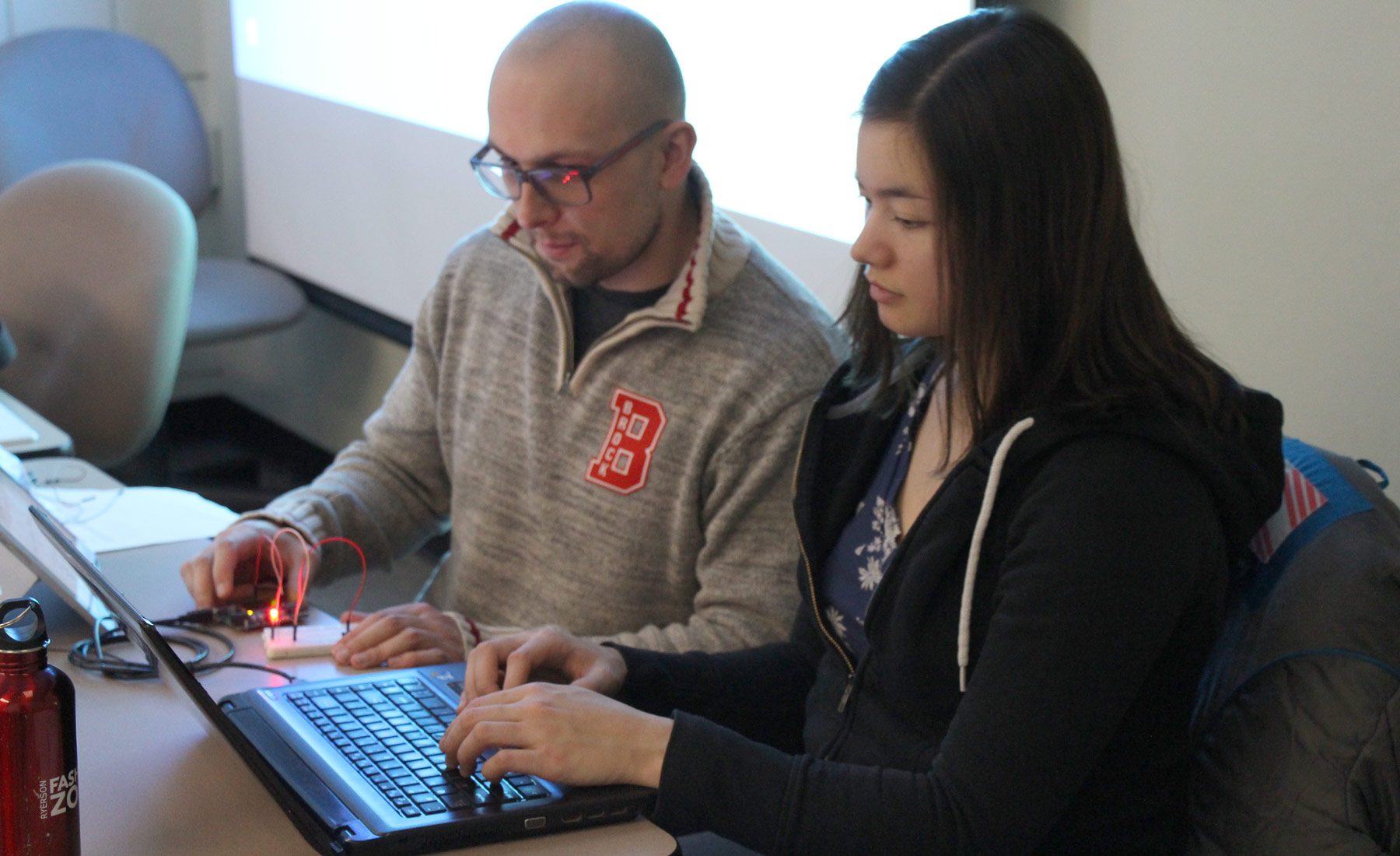 2 students hard at work on laptops 