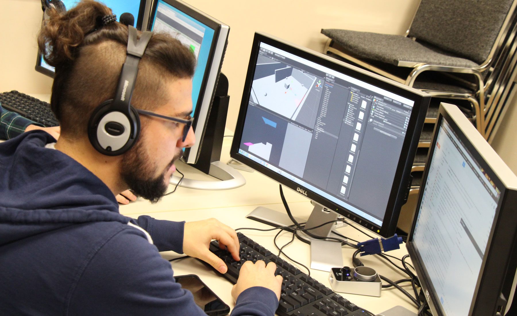 a student at work on computers doing 3d room design wearing headphones