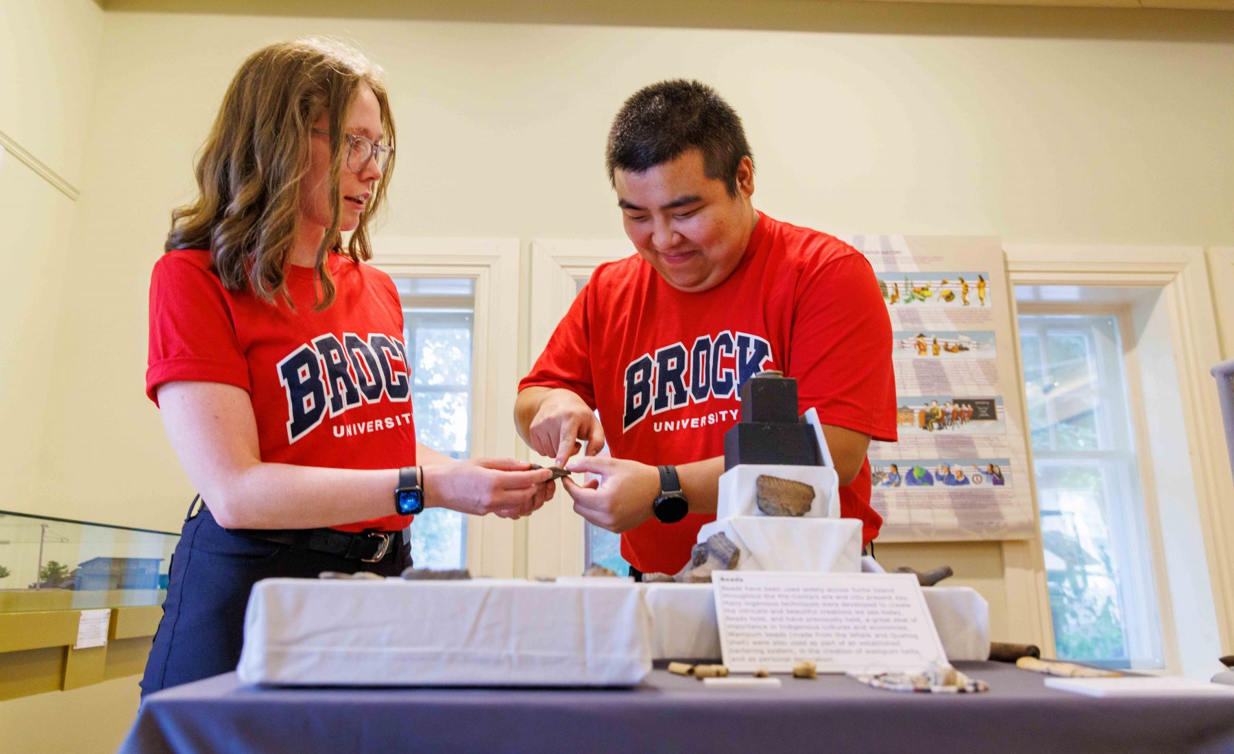 Two students in Brock shirts work on museum exhibit 