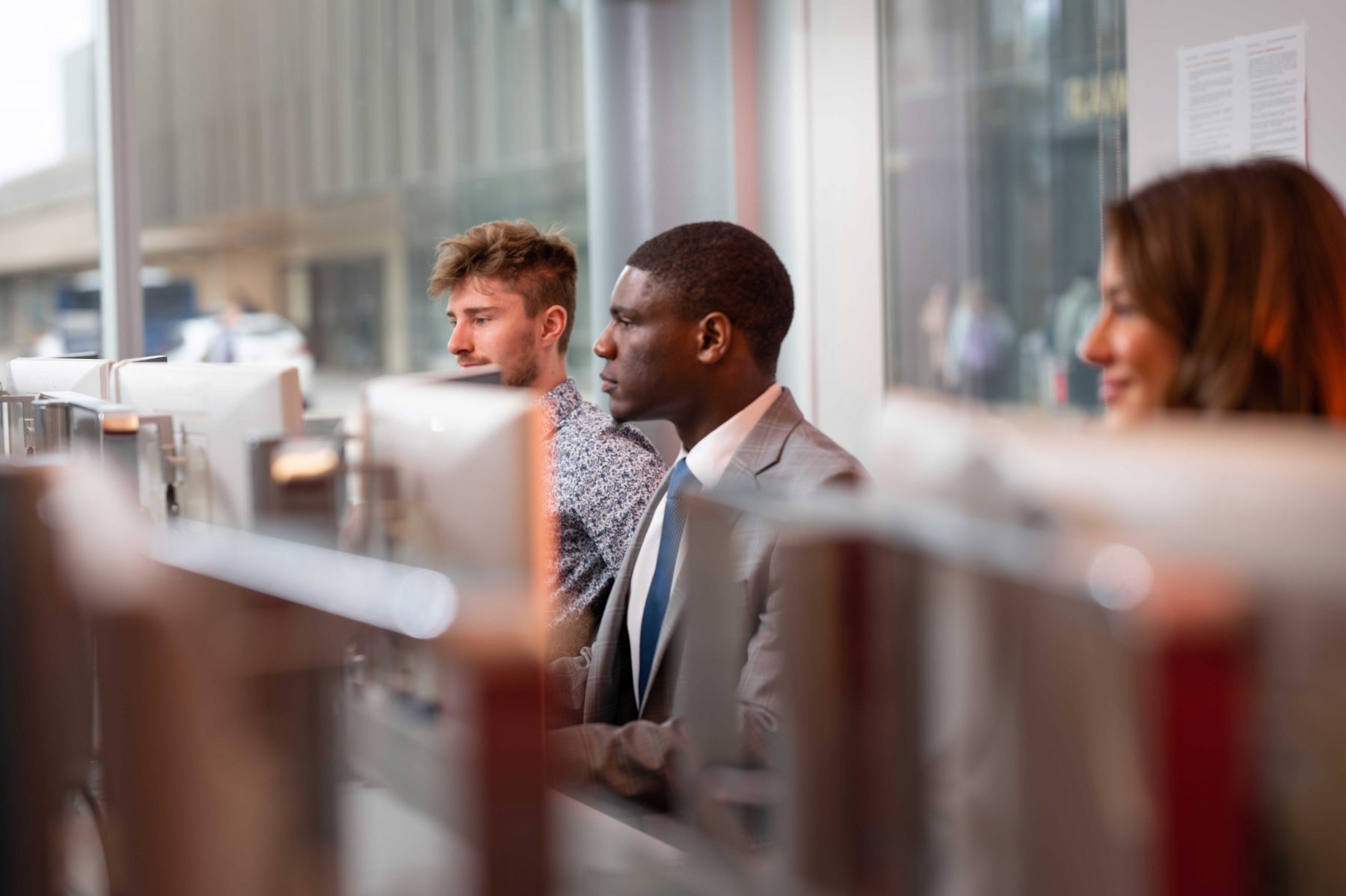 Three students dressed in business attire sit at computers at Brock University.