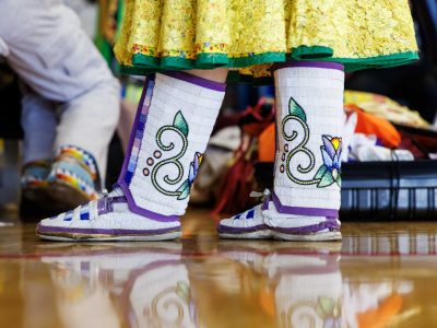 White boots with decorative flowers and purple trim are worn as part of traditional Indigenous regalia.