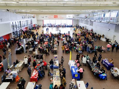A gymnasium filled with vendor tables and people dancing in the background.