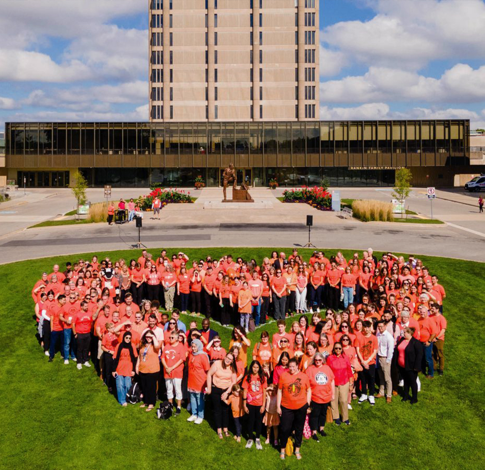 Aerial photo of Brock University campus with people standing in the shape of a heart, wearing orange shirts for Orange Shirt Day.