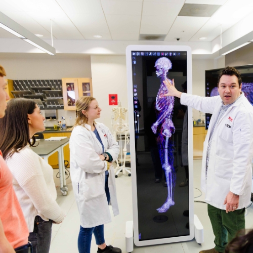 University of Portsmouth logo and Kinesiology teacher in fromnt of digital board