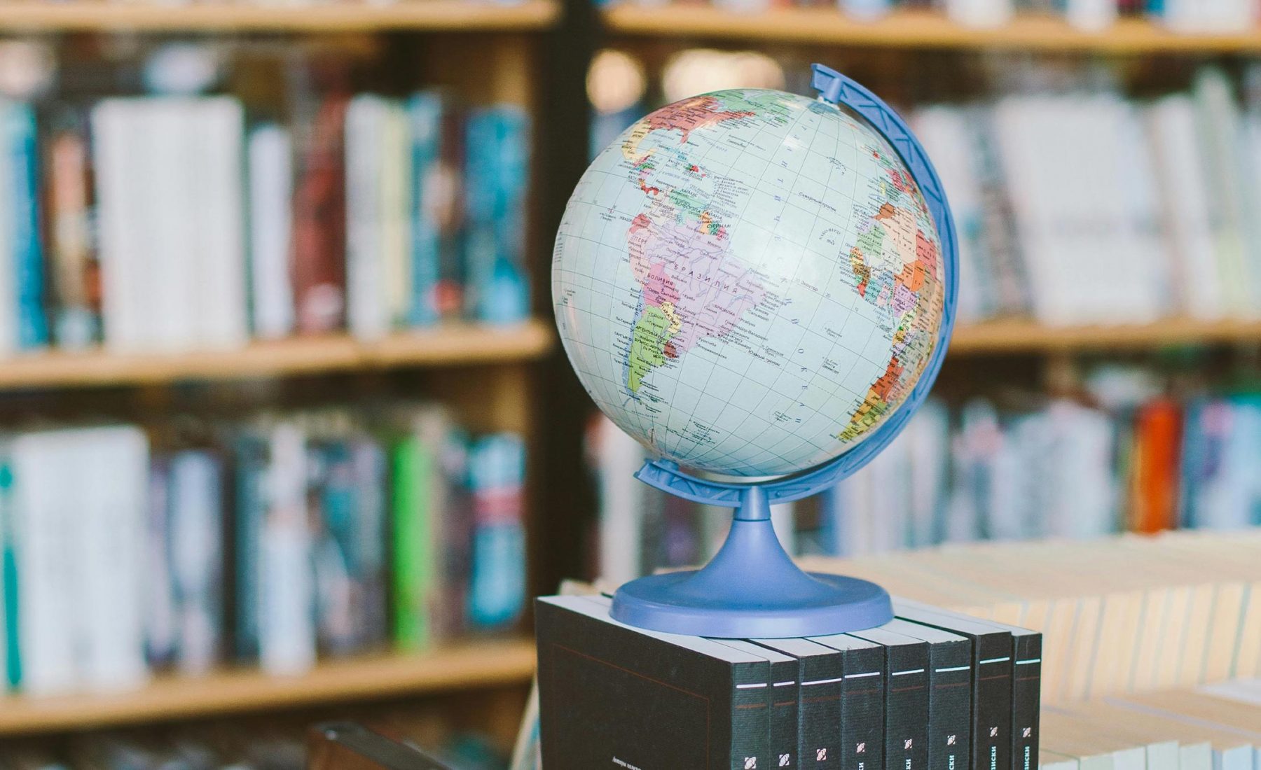 A globe in the foreground with shelves of books in the background. 