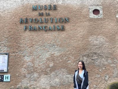 A woman poses for a photo in front of the Museum of the French Revolution in France.