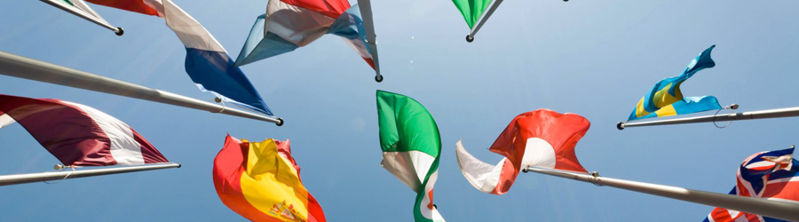 An image of international country flags , taken from below as they wave against a blue sky above.