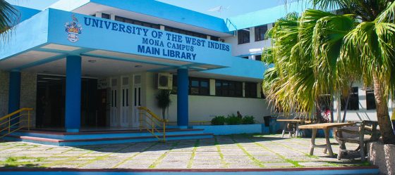 A photo of the exterior entrance to the main library at University of the West Indies Mona campus. A large palm tree in the foreground.