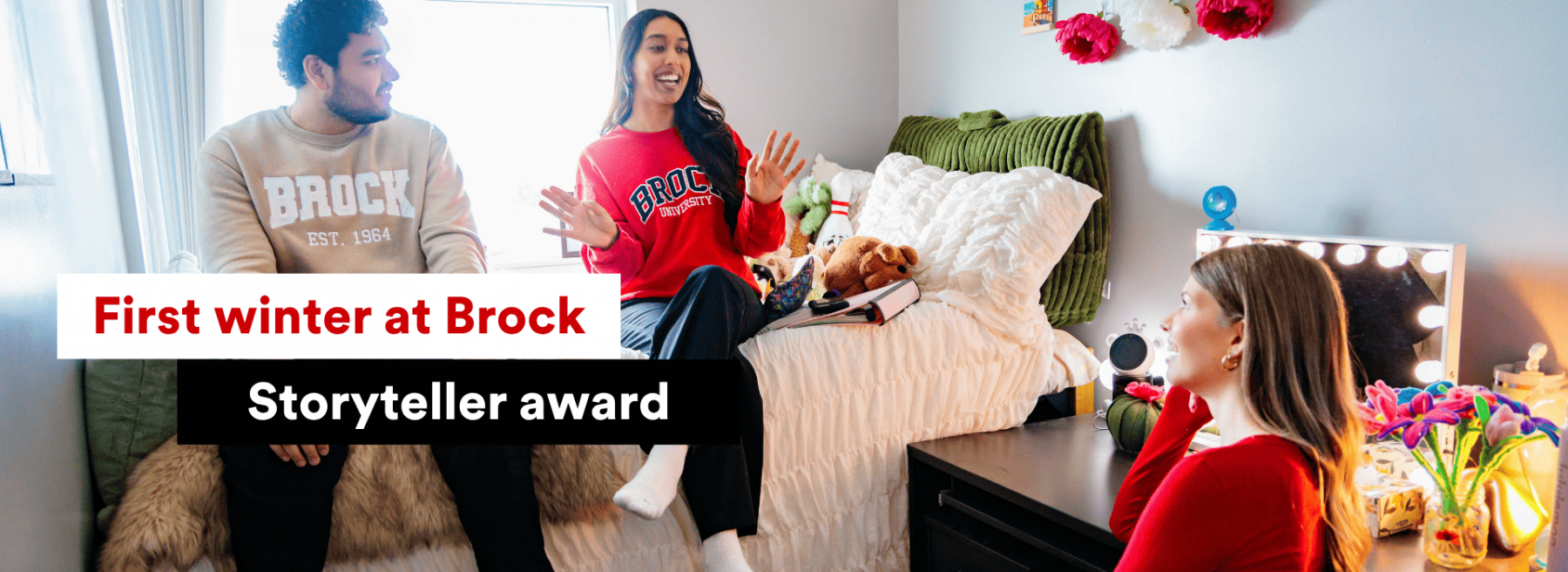 3 Brock University students in a dorm room laghing wearing Brock branded shirts