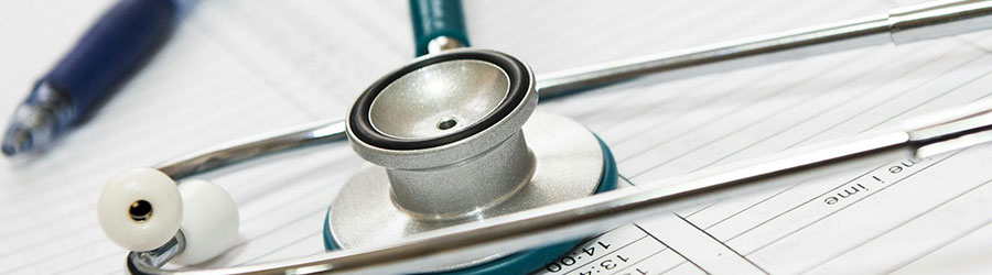 A stethoscope on a table next to a pen.