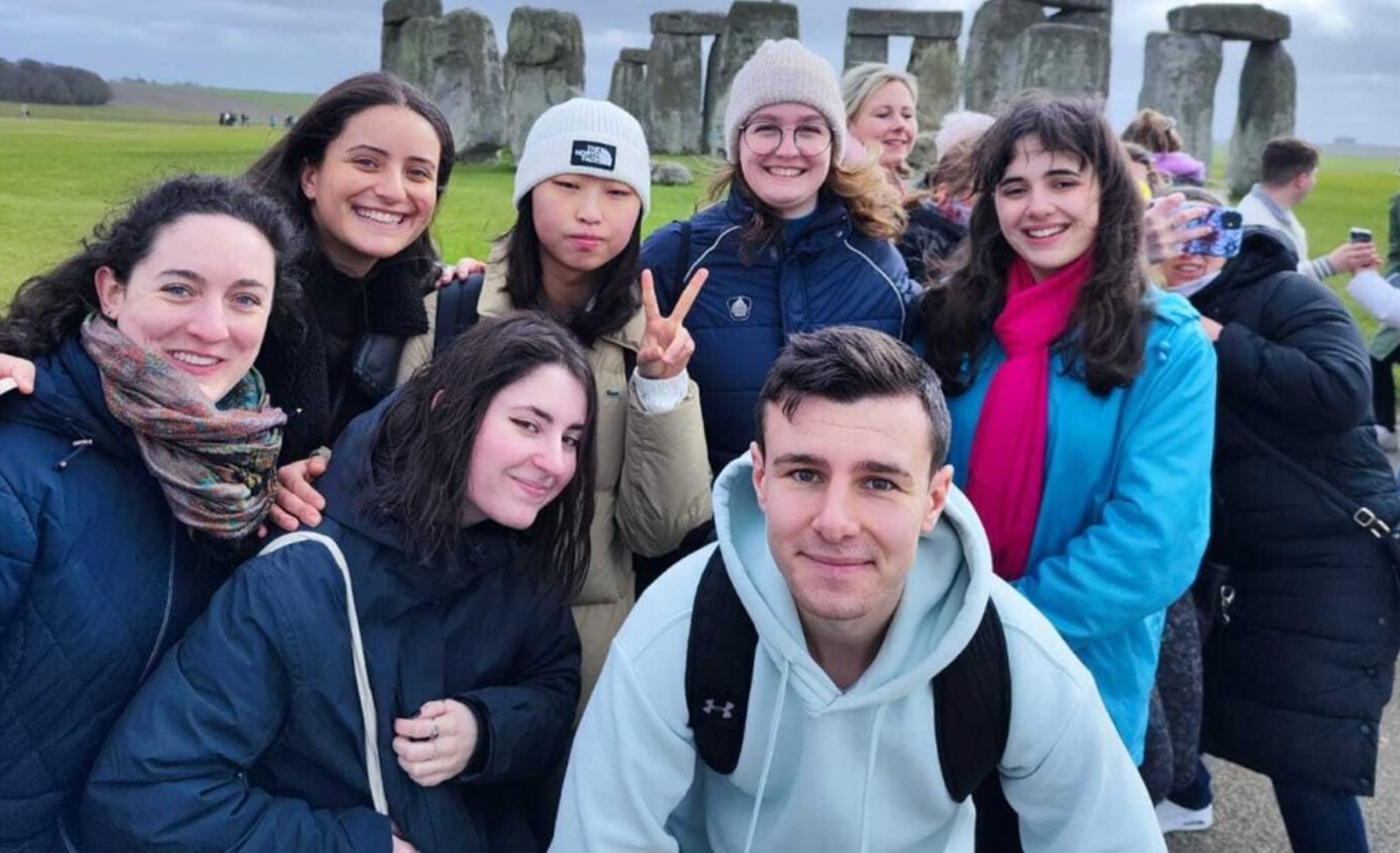 University students on exchange pose for a group selfie in front of Stone Henge. 