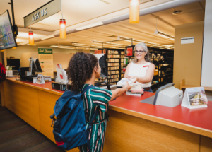 A staff member at the Ask Us desk hands a book over to a student.