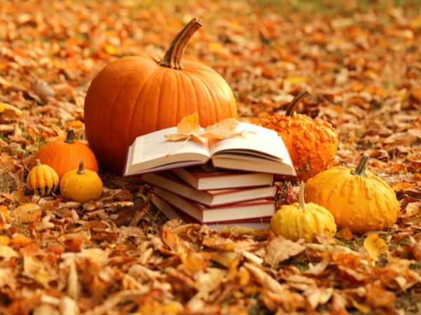A scene of autumn leaves, pumpkins, and books