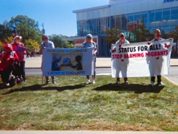 Senior citizens holding banners protest in a public space