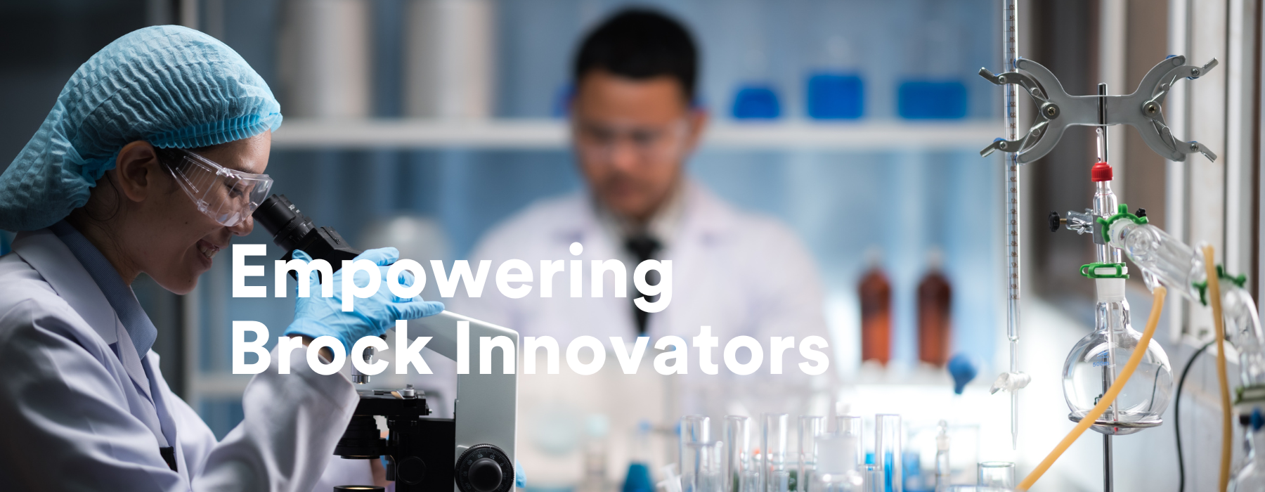 Empowering Brock Innovators text in front of a lab student at microscope and another student in a lab jacket in background