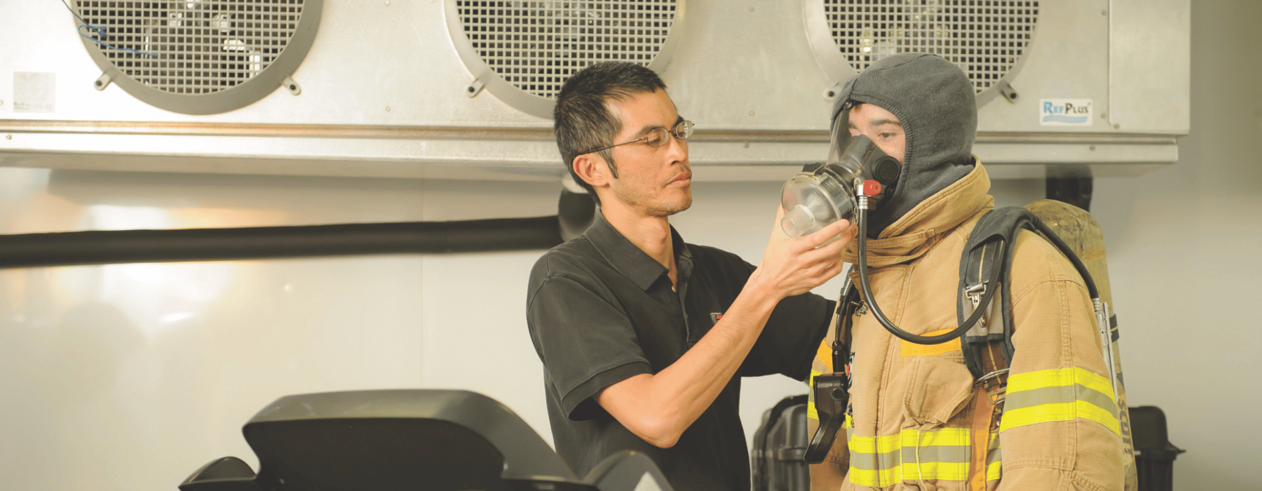 Professor helping student with oxygen mask wearing firefighter uniform 