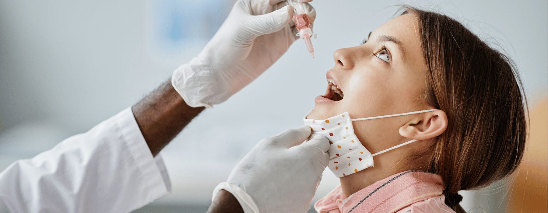 Child getting drops into mouth by physician 