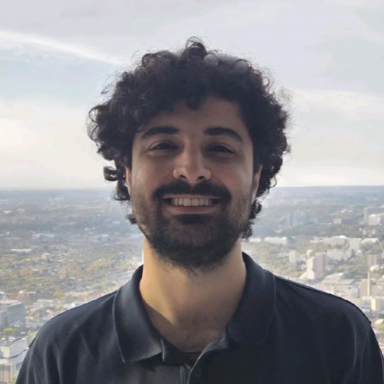Nima Jafarnia poses in black golf shirt overlooking a city