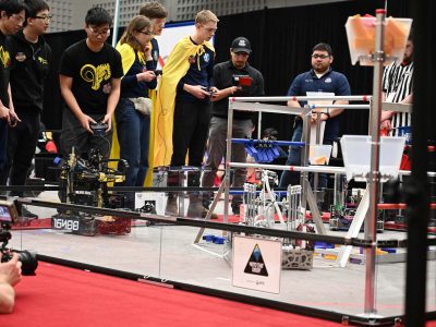 Robotics competition field with students and robots piloting their robot