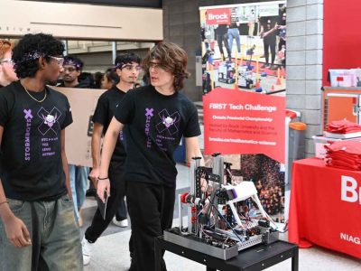 Youth robotics team transports robot past Brock university booth