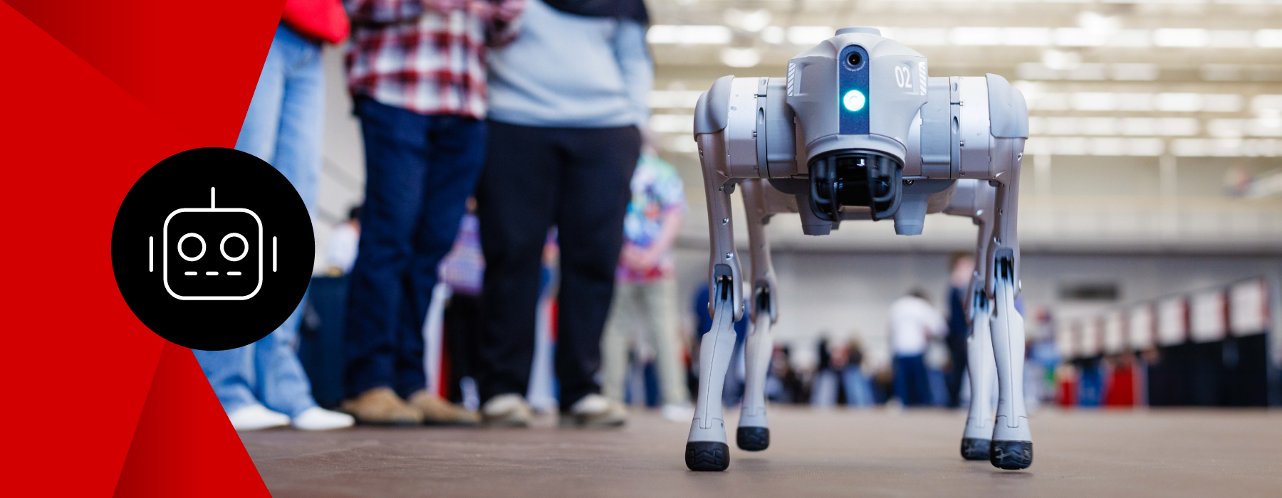A group of students watch a four-legged semi-autonomous robot being demonstrated.