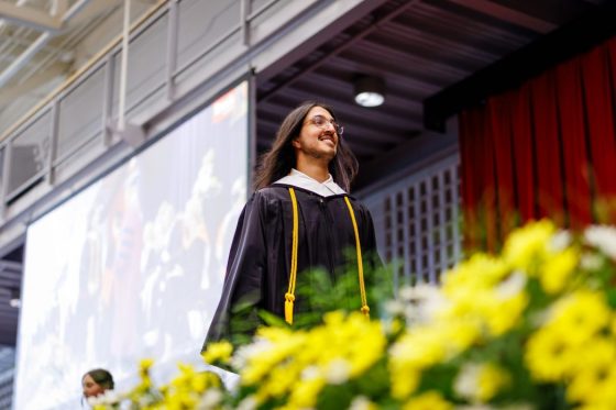 Nav Brar crosses the stage in graduation gown at convocation.