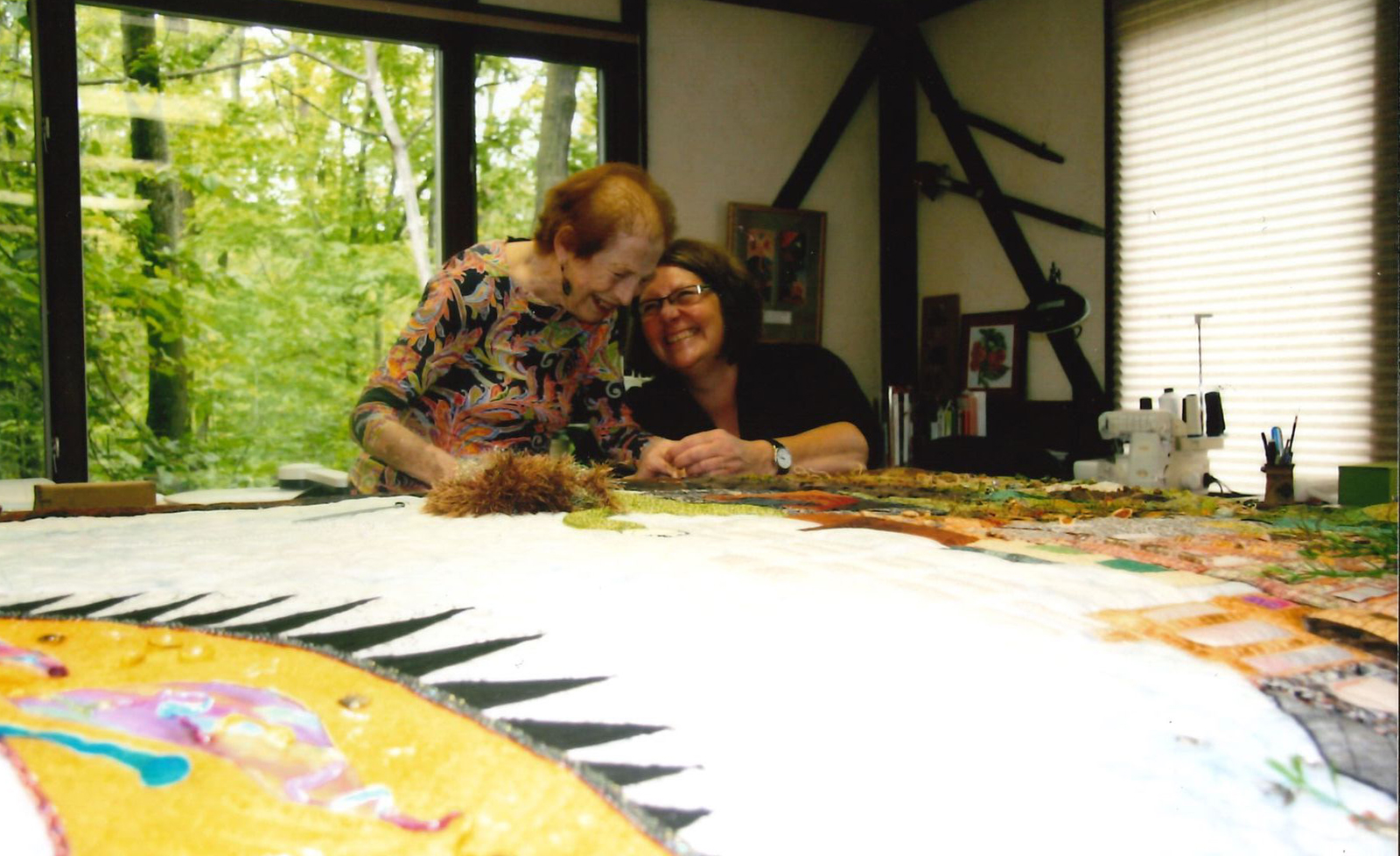 Roberta Doylend and the late Marilyn Walker working on the Tree of Learning, a nine-foot-tall quilt that incorporates uncommon fabrics and techniques from textile and fibre art to depict a dream about studying the arts, now displayed in the MIWSFPA