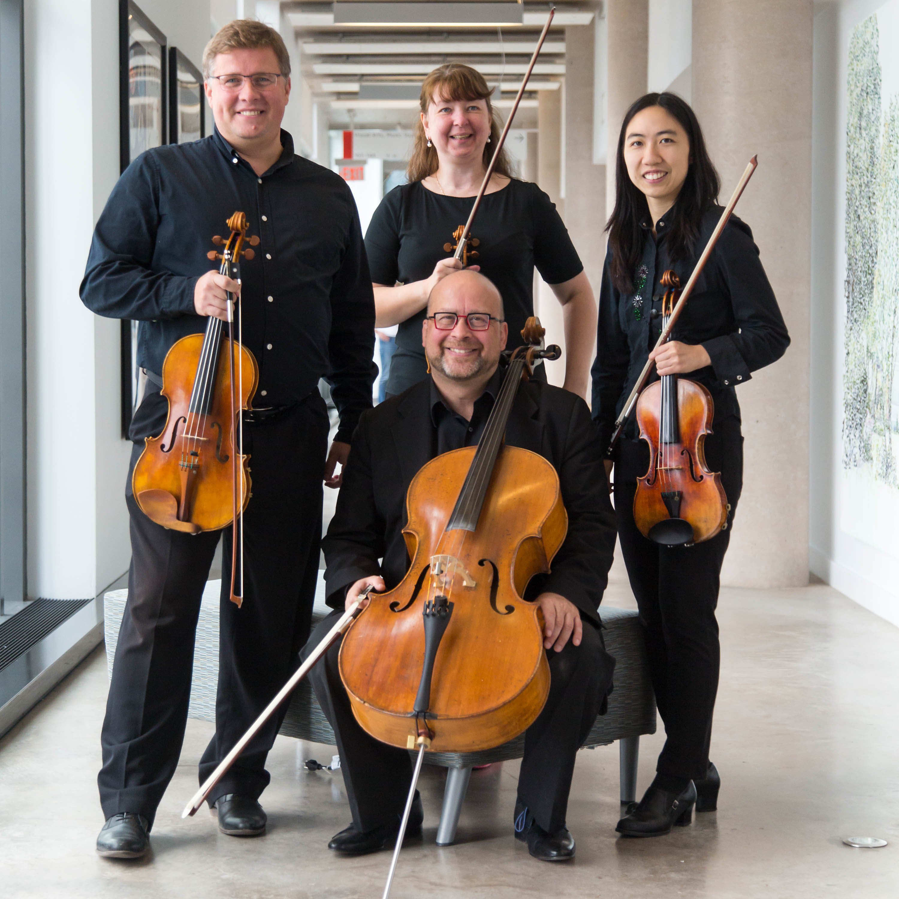Walker String Quartet holding instruments in hallway