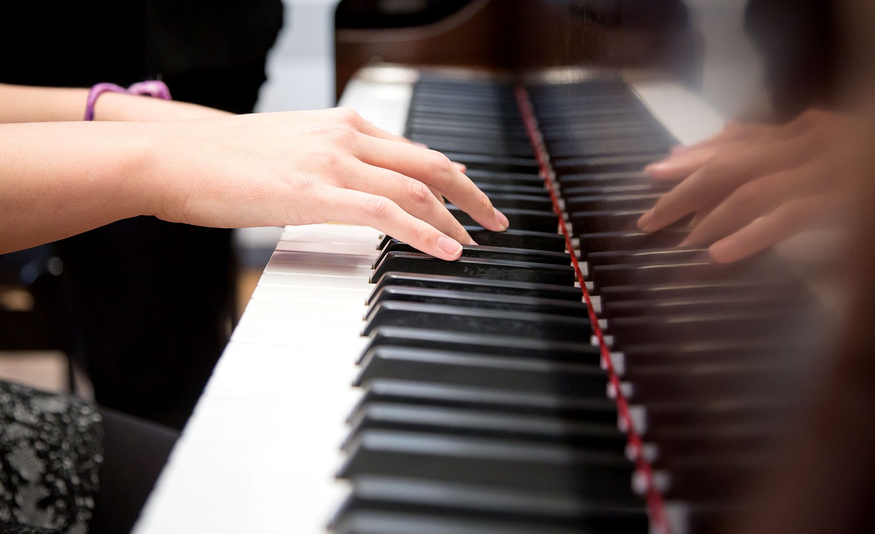 Female student playing piano side-by-side with Dr. Karin Di Bella 