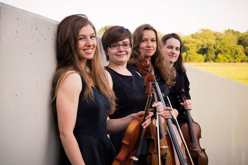 4 string orchestra musicians leaning against a wall