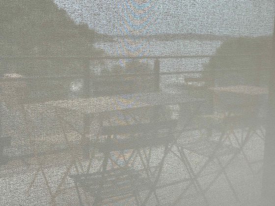 Grainy image of balcony with empty chairs overlooking the sea.