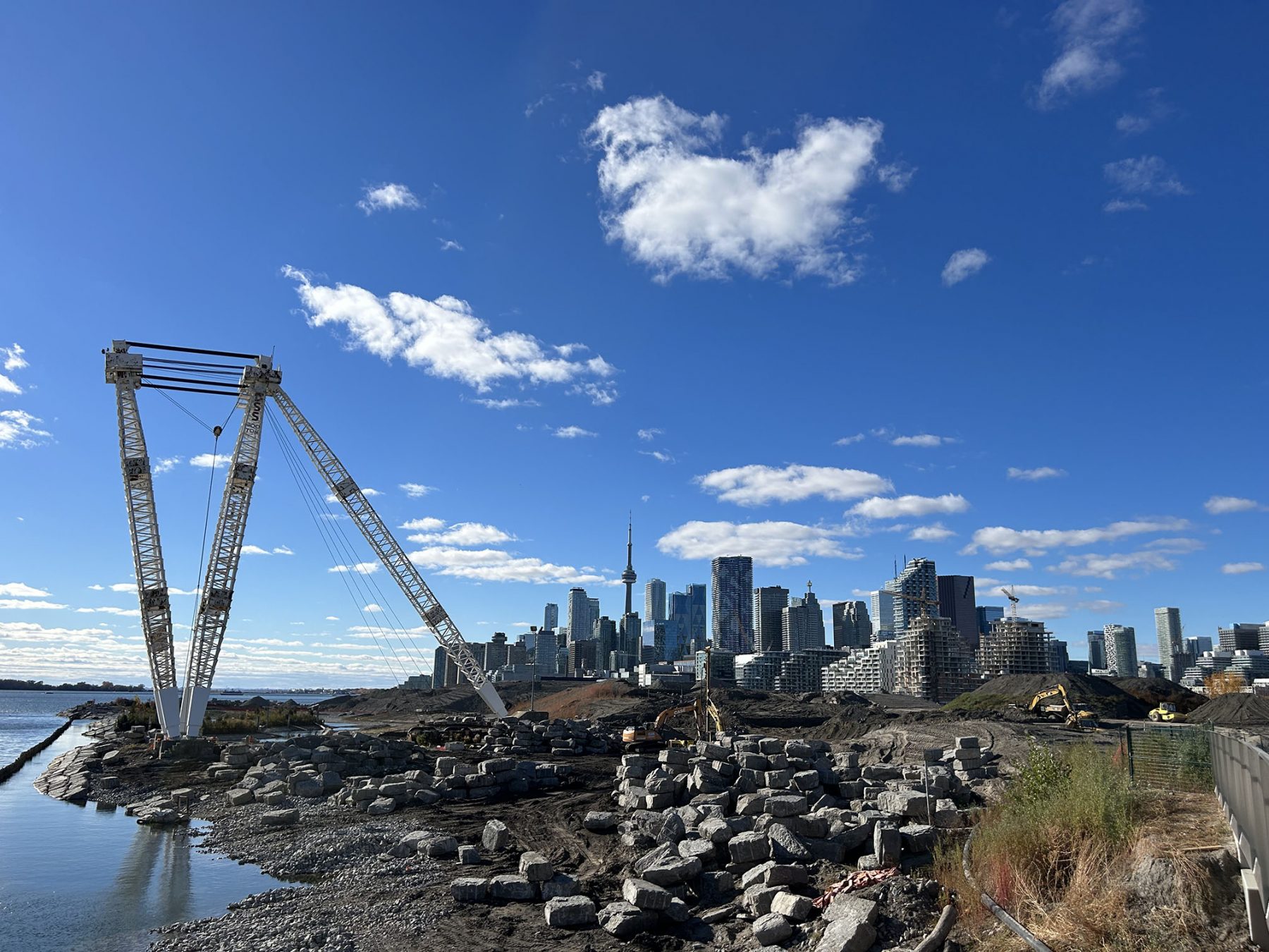 Crane on the shore of lake ontario moving boulders with toronto skyline in background