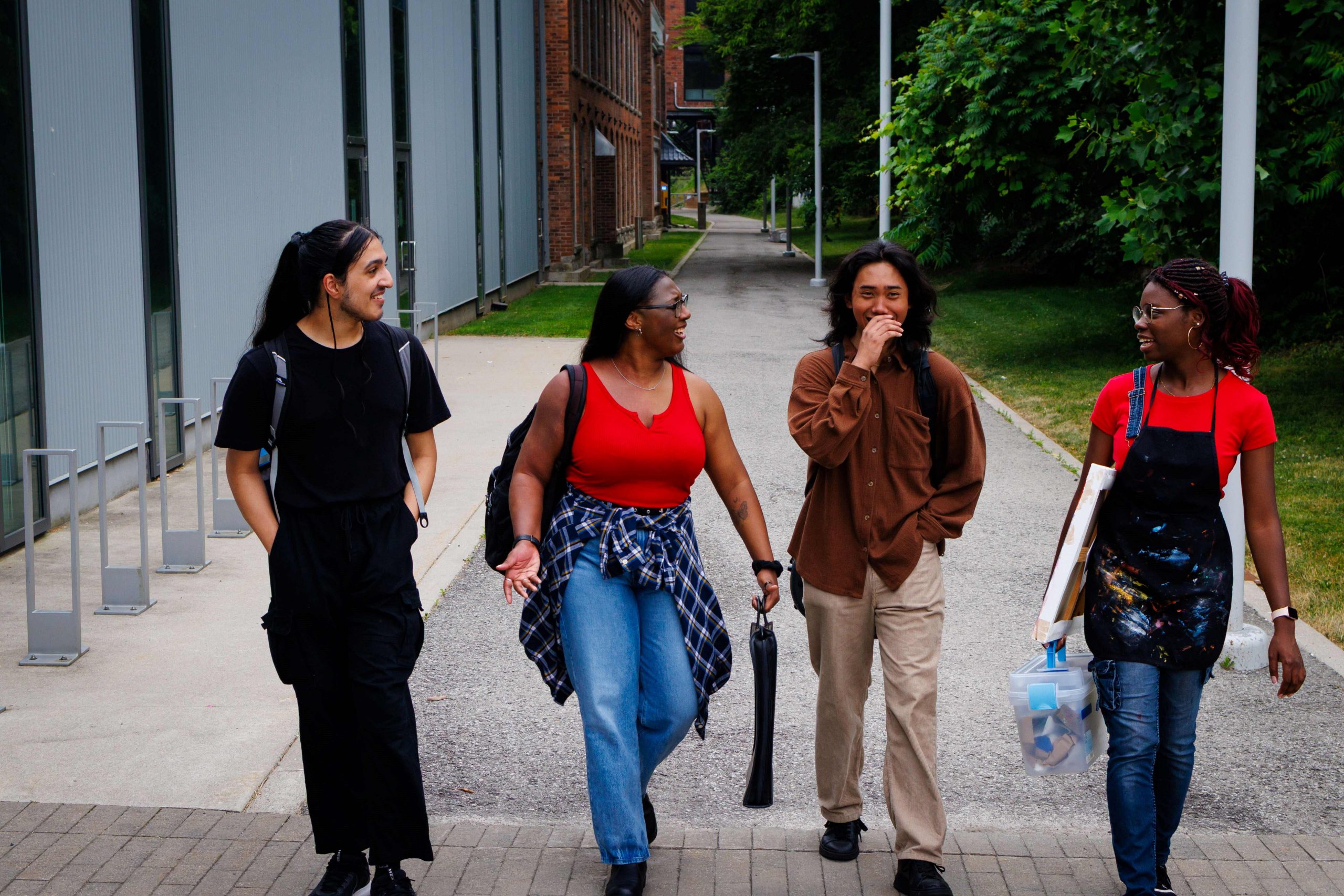 4 students walk and talk behind the Marilyn I. Walker School of Fine and Performing Arts.