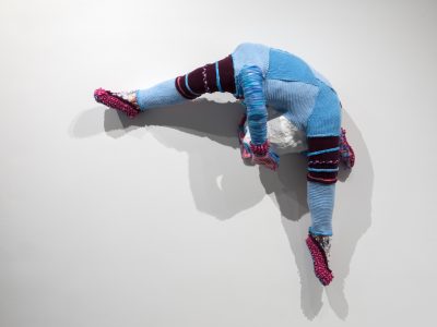 abstract sculpture of a colourful figure hanging on a white wall