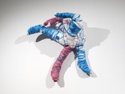 abstract sculpture of a colourful figure hanging on a white wall