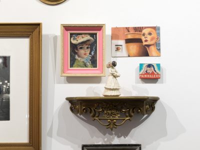 group of paintings in ornate frames and a shelf with a figurine on top